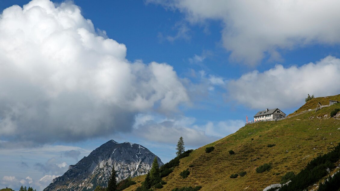 Eine wunderschöne Berglandschaft mit sanften Hügeln und einer klaren blauen Himmel. Im Hintergrund ist ein Haus und ein majestätischer Berg zu sehen. | © Hans-Peter Steiner