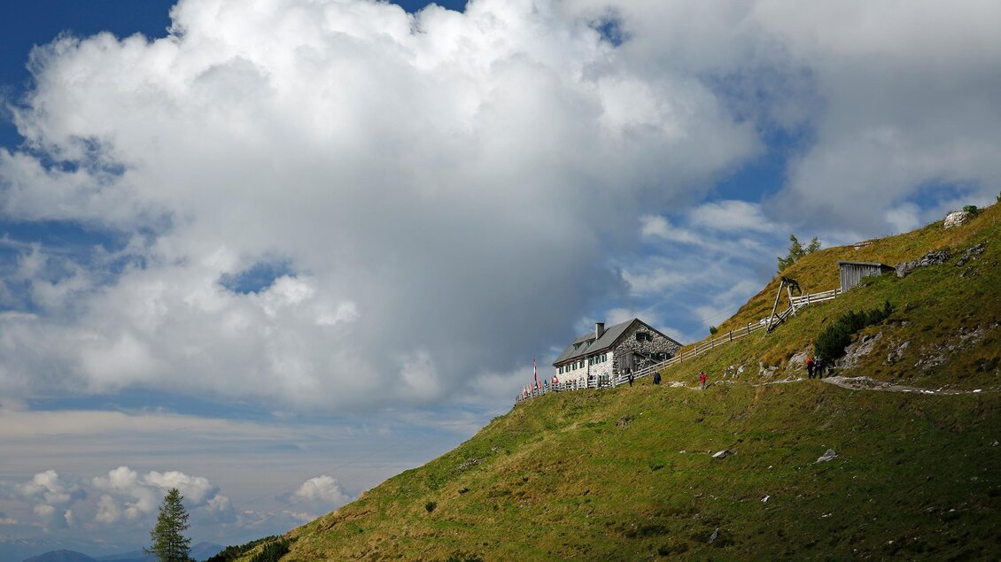 Ein malerisches Berghaus auf einer grünen Wiese unter einem wolkigen Himmel. Die Landschaft ist ruhig und bietet einen wunderschönen Ausblick. | © Hans-Peter Steiner