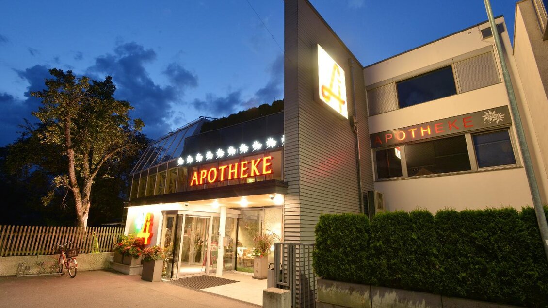 Eine Apotheke bei Nacht mit erleuchteter Fassade. Der Eingangsbereich ist einladend gestaltet. | © Edelweiss Apotheke