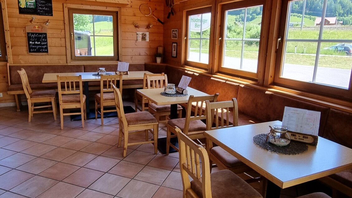 Ein gemütliches Restaurant mit Holzwänden und großen Fenstern. Es sind Tische und Stühle vorhanden, die für Gäste bereitstehen. | © FREI-ZEIT by Enns
