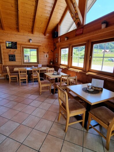 A cozy restaurant with wooden walls and large windows. There are tables and chairs available for guests. | © FREI-ZEIT by Enns