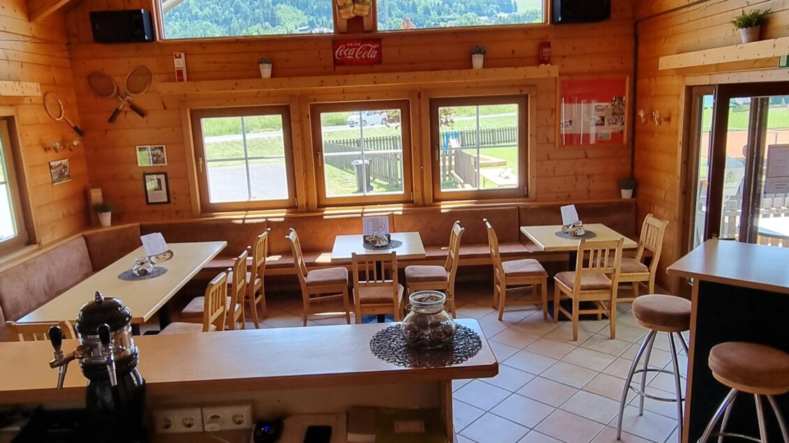 Ein gemütlicher Innenraum mit Holzwänden und einer hohen Decke. Die Fenster bieten einen schönen Blick auf die Landschaft. | © FREI-ZEIT by Enns