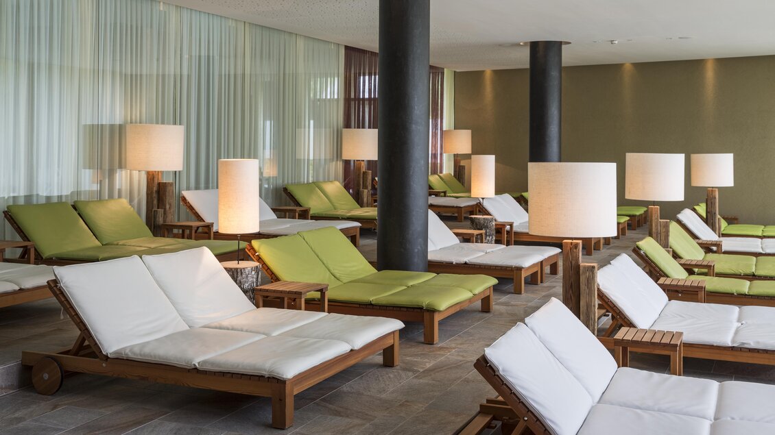 Ein eleganter Entspannungsbereich mit Liegen in Weiß und Grün. Weiche Beleuchtung und moderne Einrichtung schaffen eine ruhige Atmosphäre. | © Falkensteiner Hotel Schladming/ Fotograf Walter Luttenberger