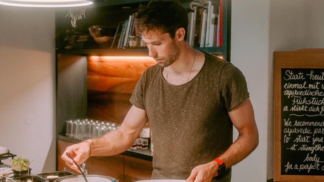 Ein Mann nimmt sich was vom Frühstücksbuffet. Auf dem Tisch sind verschiedene Utensilien und Lebensmittel zu sehen. | © Stadthotel brunner