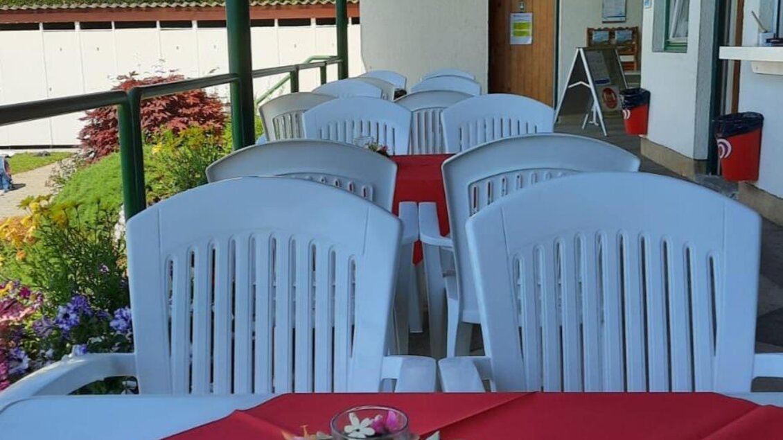 Eine Terrasse mit weißen Stühlen und roten Tischdecken. Auf den Tischen stehen kleine Blumenschmuckstücke. | © Gemeinde Mitterberg-Sankt Martin