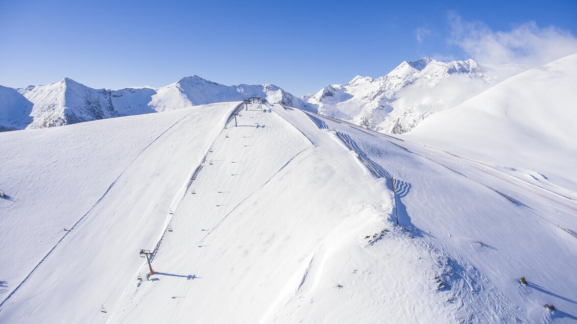 Eine schneebedeckte Berglandschaft mit klar blauem Himmel. Die Pisten sind gut sichtbar und laden zum Skifahren ein. | © Johannes Absenger