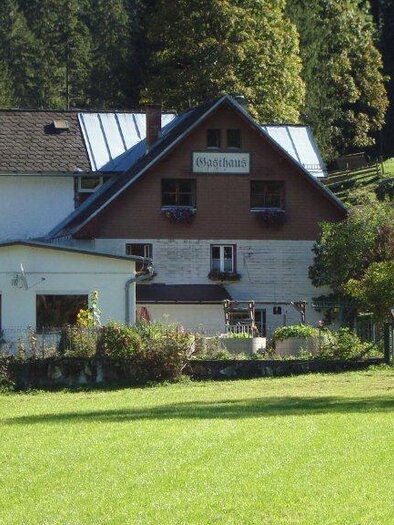 A charming house in a rural setting, surrounded by green meadows and trees. Rolling hills are visible in the background. | © Familie Reichart