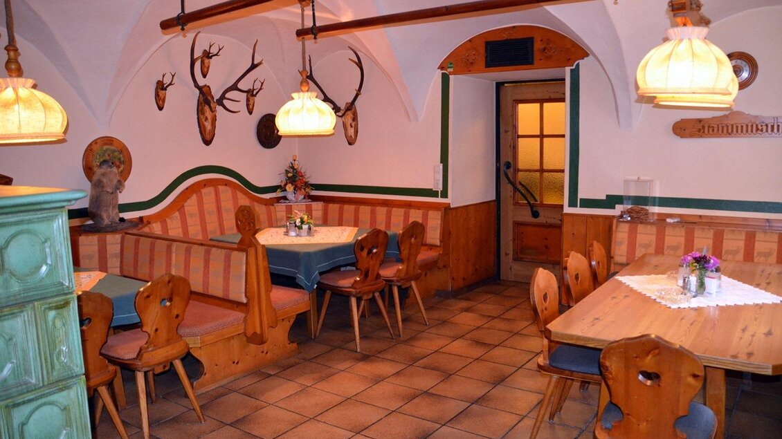 Ein gemütliches Restaurant mit Holzmöbeln und warmem Licht. An den Wänden hängen Hirschgeweihe, was eine rustikale Atmosphäre schafft. | © Christian Tritscher