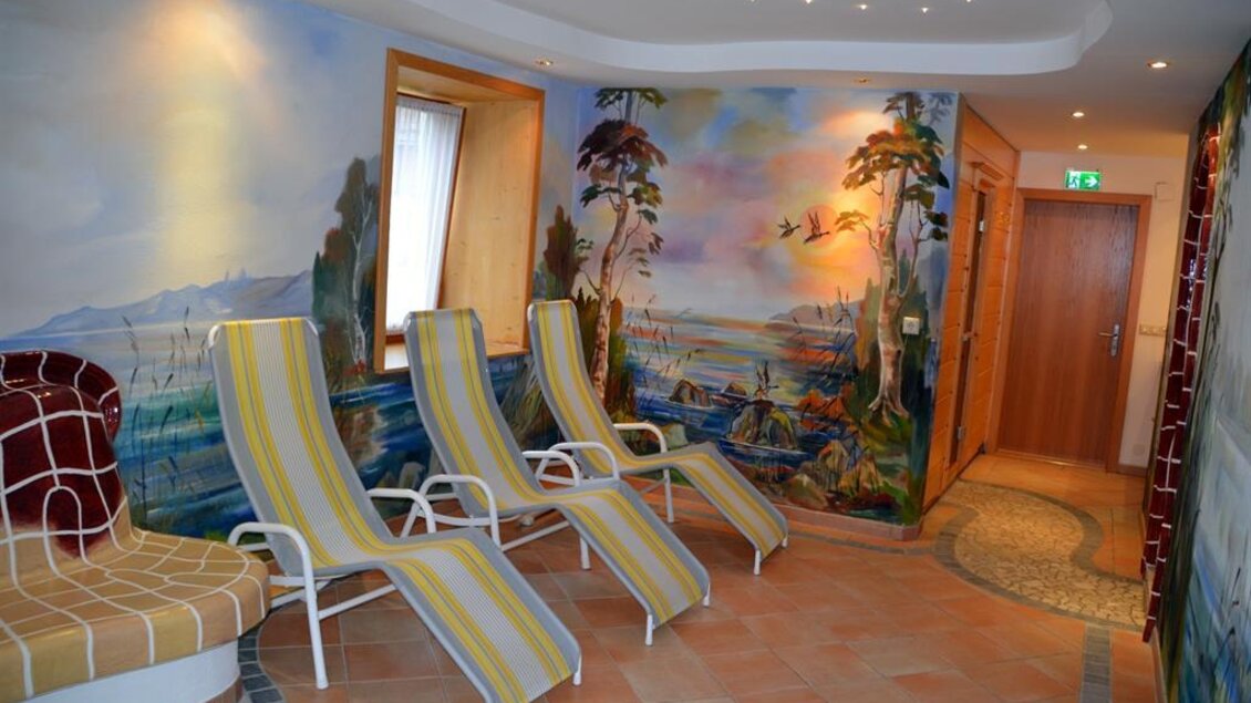 Ein entspannender Raum mit Liegen und bunten Wandmalereien. Die Atmosphäre ist ruhig und einladend. | © Christian Tritscher