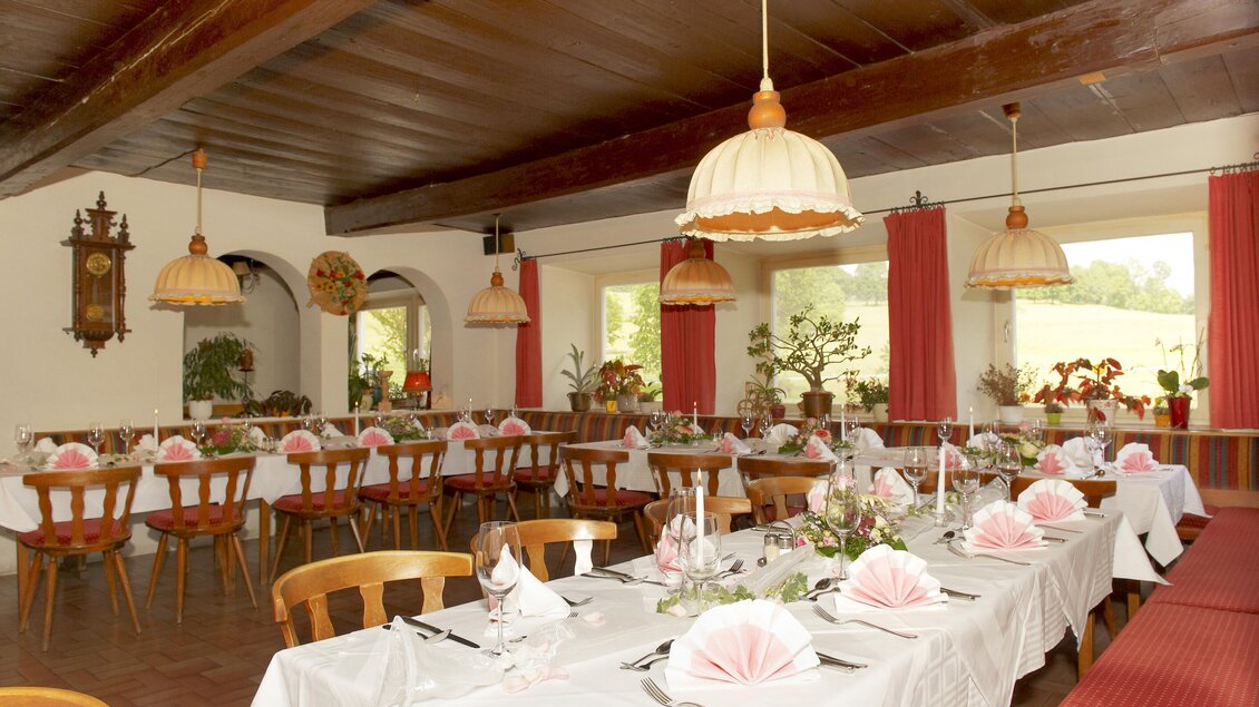 Ein einladendes Restaurant mit stilvollen Tischen und dekorierten Servietten. Die warmen Farbtöne und die stimmungsvolle Beleuchtung schaffen eine gemütliche Atmosphäre. | © Gasthof Stockerwirt