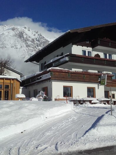 Ein charmantes Gebäude in den Bergen, umgeben von Schnee. Der Himmel ist klar und die Landschaft ist malerisch. | © Gasthof Türlspitz