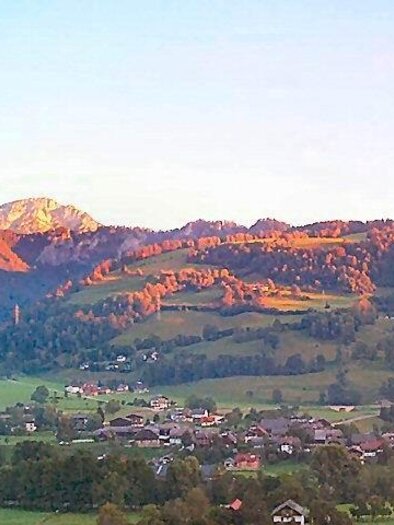 A picturesque landscape with gentle hills and a clear sky. In the foreground, there are green meadows and small houses. | © Gemeinde Michaelerberg-Pruggern