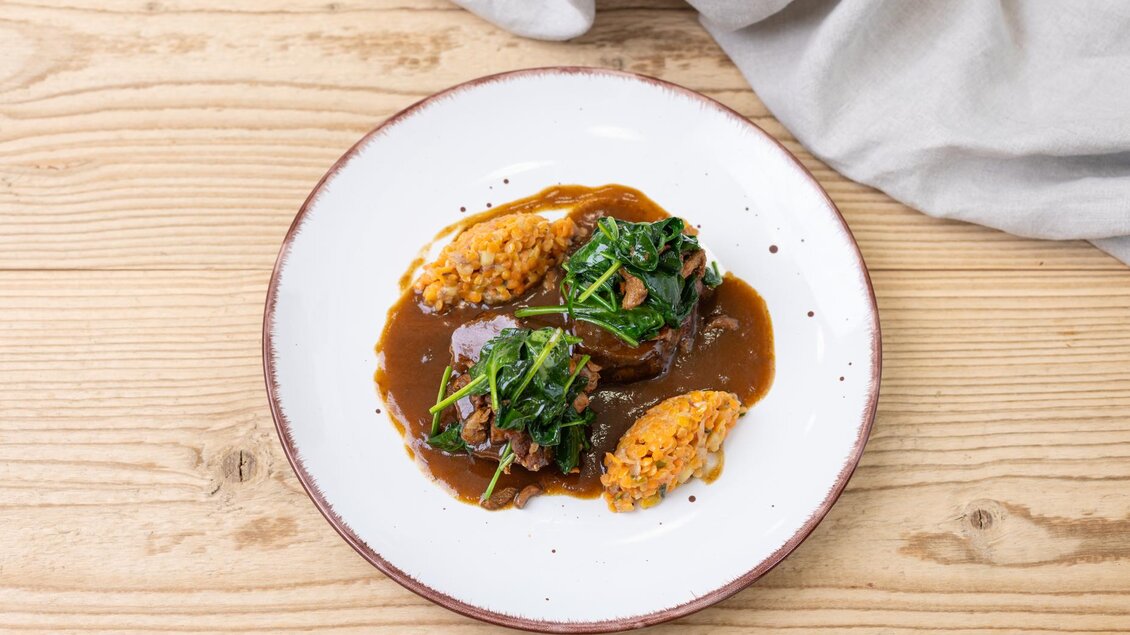 Ein Teller mit herzhaftem Fleisch in einer würzigen Sauce, garniert mit frischem Gemüse. Dazu cremiger Reis in zwei Portionen. | © ©Martin Huber