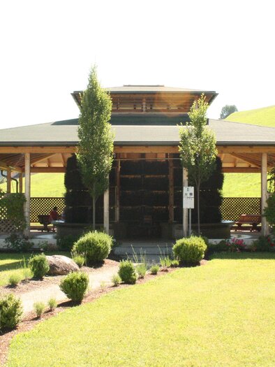 A beautiful wooden building with a green roof and large windows. Surrounded by well-maintained lawns and trees. | © Infobüro Gröbming