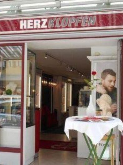 An inviting shop named "HERZKLOPFEN." A person stands at the entrance and looks outside. | © Herzklopfen