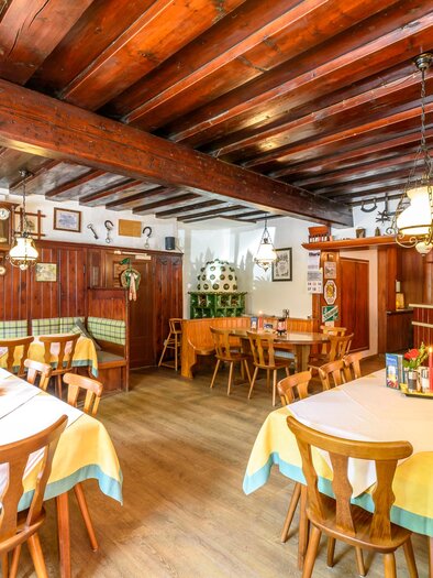 A cozy restaurant with a wooden ceiling and bright tables. The atmosphere is inviting and traditional.