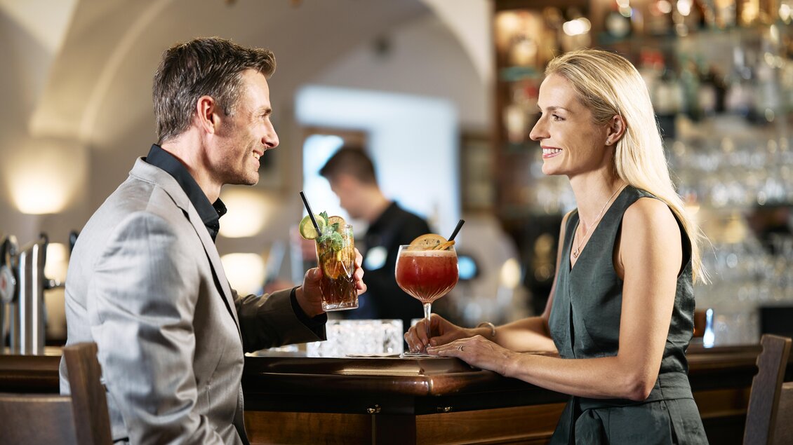 Ein elegantes Paar sitzt an der Bar und genießt ihre Cocktails. Die Atmosphäre ist stilvoll und einladend. | © Thomas Sattler