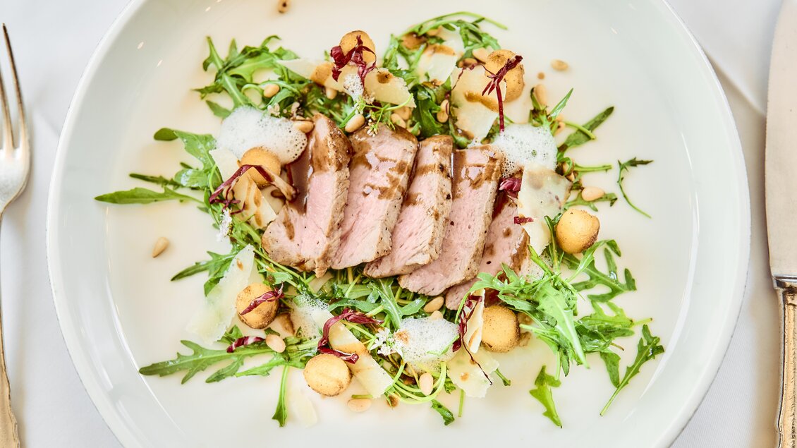 Ein hübsches Gericht mit zartem Fleisch, frischem Rucola und bunten Beilagen. Die Präsentation ist elegant und ansprechend. | © Thomas Sattler