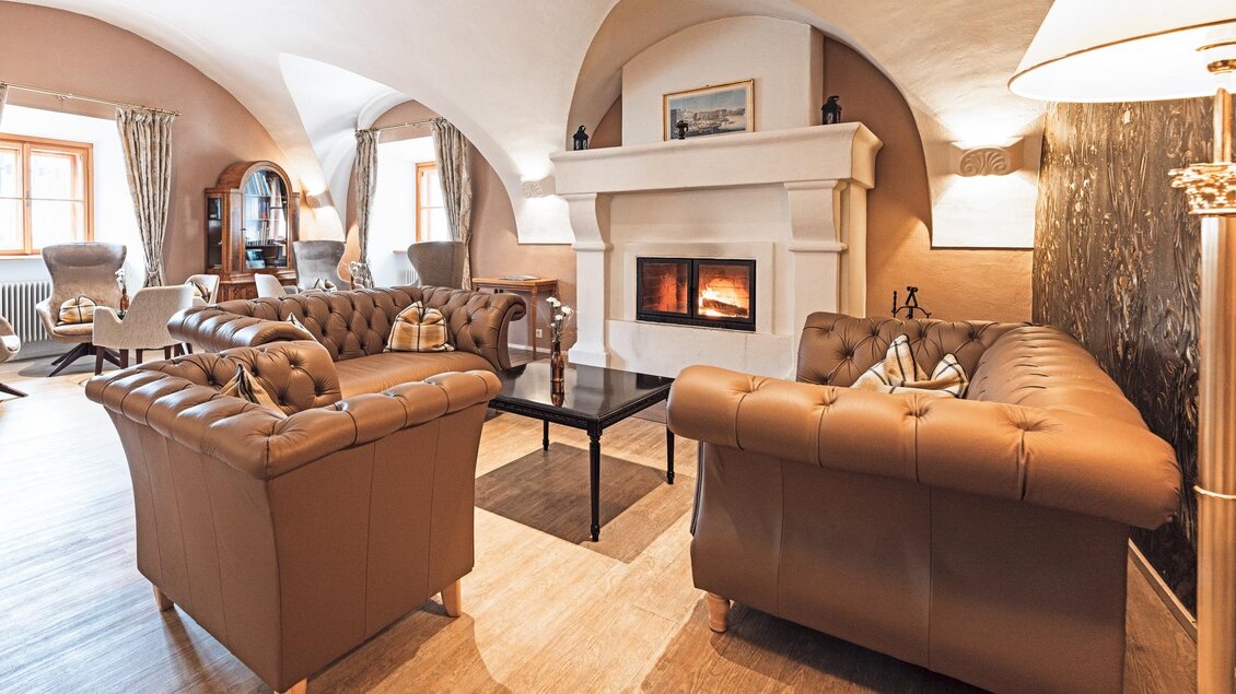 Ein elegantes Wohnzimmer mit braunen Ledersesseln und einem modernen Kamin. Gemütliche Atmosphäre mit warmem Licht und Holzfußboden. | © Thomas Sattler