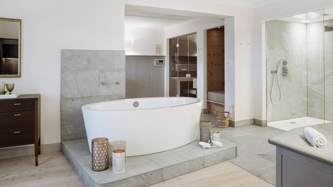 Ein modernes Badezimmer mit einer freistehenden Badewanne und eleganen Fliesen. Daneben befindet sich eine begehbare Dusche und ein stilvolles Waschbecken. | © Richard Schabetsberger