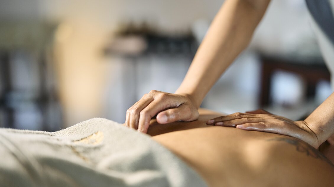 Eine Person erhält eine Massage auf einem Behandlungstisch. Die Atmosphäre wirkt entspannend und friedlich. | © Thomas Sattler