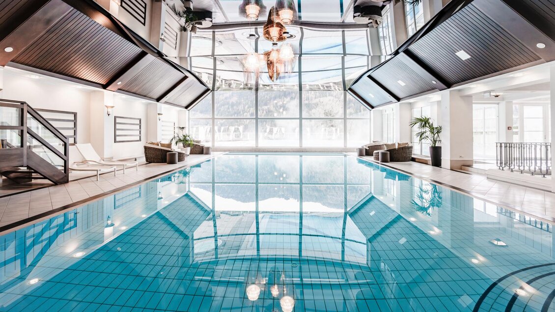 Ein modernes Hallenbad mit klarem, blauem Wasser. Große Fenster sorgen für viel natürliches Licht und eine entspannende Atmosphäre. | © Tom Sattler
