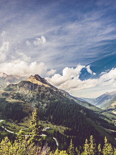 An impressive mountain landscape with high peaks and wide valleys. The sky is cloudy and the green of the forests is vivid. | © Lupi Spuma