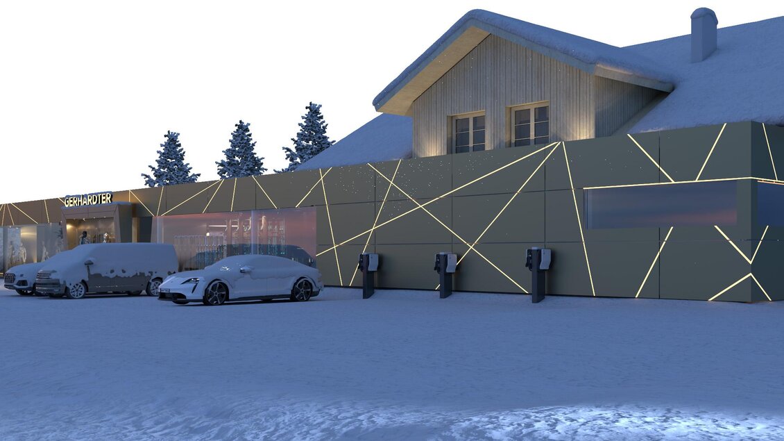 Ein modernes Gebäude mit einem ungewöhnlichen, leuchtenden Design liegt im Schnee. Parkende Autos sind im Vordergrund sichtbar. | © Intersport Gerhardter