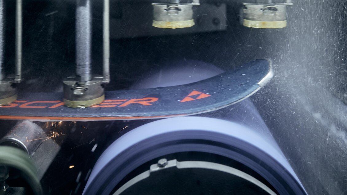 Eine Skifläche wird mit einer Maschine bearbeitet, während Funken sprühen. Die Umgebung ist industriell und technisch geprägt. | © Intersport Gerhardter