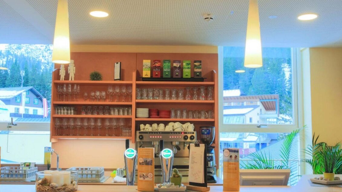 Eine moderne Café-Theke mit einer Vielzahl von Getränken und Gläsern. Im Hintergrund sind die Berge und die Natur sichtbar. | © Jufa Hotel Planneralm