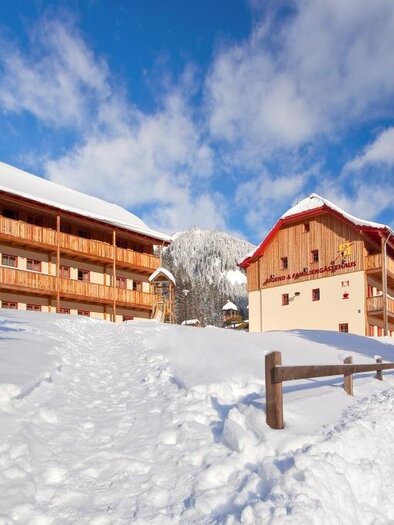 A snow-covered area with two charming Tyrolean houses. The sky is clear and blue, perfect for winter activities. | © Jufa Donnersbachwald