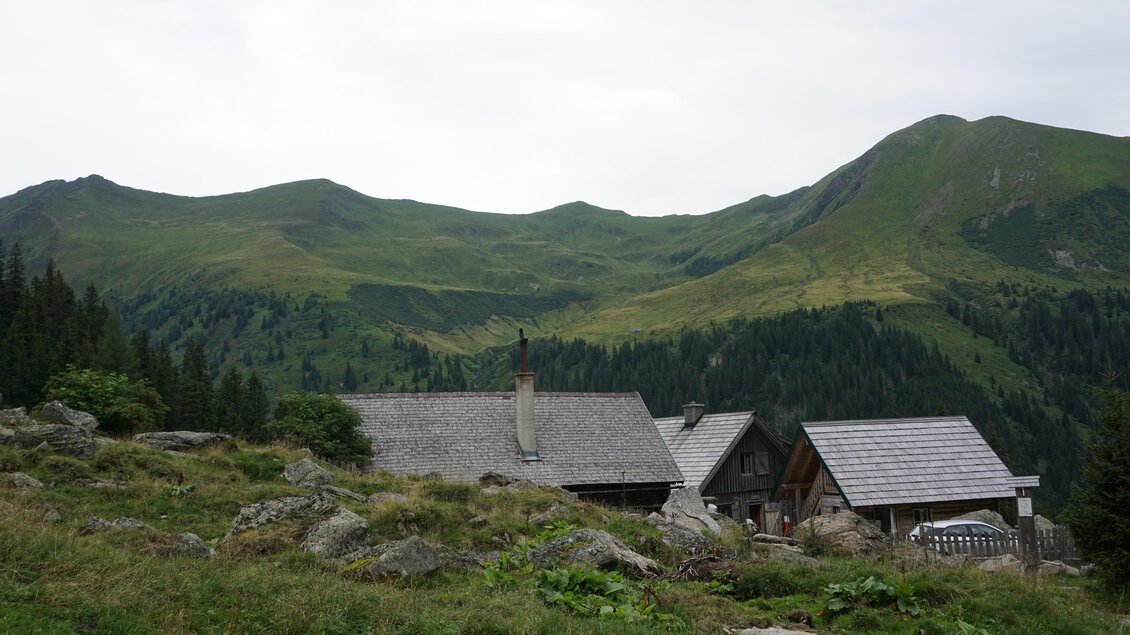 Eine malerische Landschaft mit grünen Bergen und traditionellen Hütten. Der Himmel ist bewölkt und die Umgebung wirkt ruhig und friedlich. | © Naturpark Sölktäler