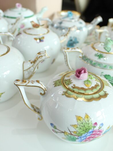 A series of elegant porcelain teapots with colorful floral patterns. The pots are delicately adorned and are placed on a white table. | © Symbolfoto Pixabay