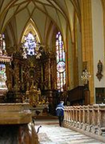 A majestic church with high ceilings and colorful windows. Inside, there are wooden benches and a magnificent altar. | © Katholische Pfarrkirche Gröbming