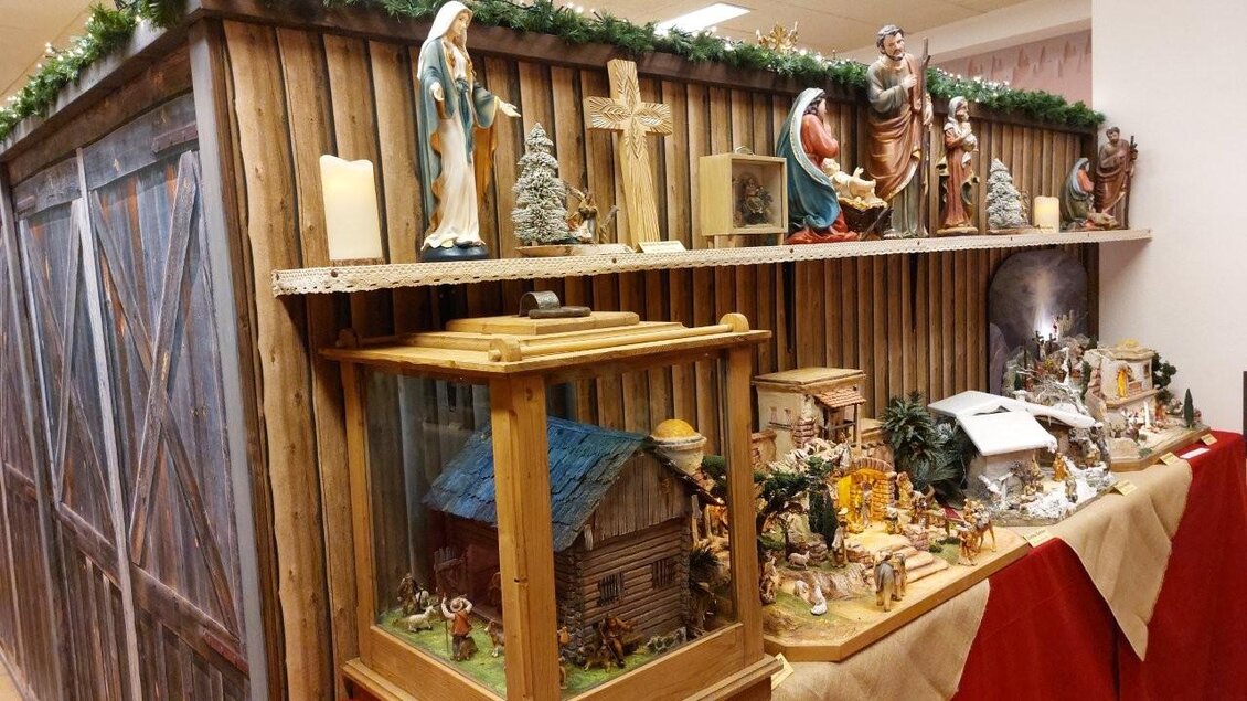 Eine festliche Ausstellung mit verschiedenen Weihnachtsfiguren und einer Krippe. Im Hintergrund sind Holzdekor und Weihnachtsschmuck zu sehen. | © Gerald Gerhardter