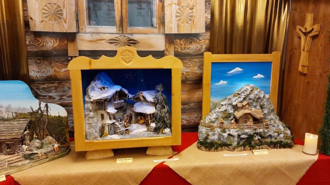 Drei kunstvoll gestaltete Weihnachtsdarstellungen in einem festlichen Umfeld. Jede Szene zeigt winterliche Landschaften mit Hütten und Bergen. | © Gerald Gerhardter