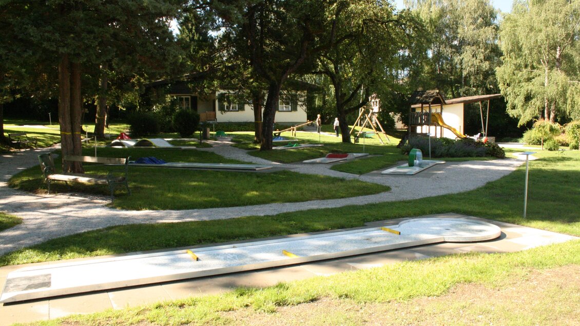Ein weitläufiger Außenbereich mit Rasenflächen, Bäumen und verschiedenen Spielmöglichkeiten. Im Hintergrund sind ein Spielplatz und ein Haus sichtbar. | © TVB Gröbminger Land 