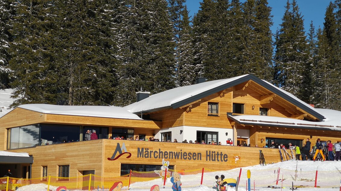 Eine gemütliche Berghütte im Schnee mit vielen Besuchern. Umgeben von schneebedeckten Bäumen und bunten Figuren im Winterwald. | © Gerald Petter