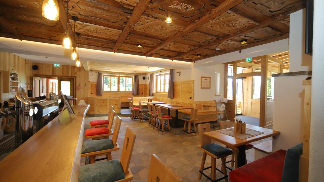 Eine gemütliche Gaststube mit Holzdekor, einem langen Tisch und gemütlichen Stühlen. Große Fenster sorgen für viel Tageslicht und eine einladende Atmosphäre. | © Gerald Petter