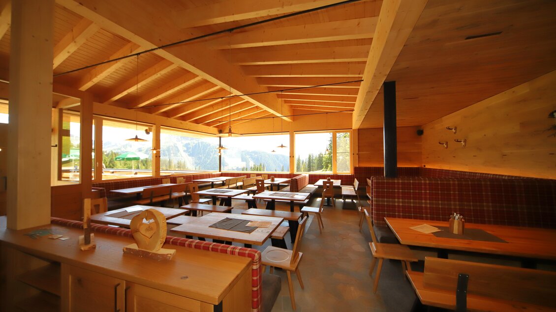 Ein gemütliches Restaurant mit Holzmöbeln und großen Fenstern. Der Blick geht auf eine schöne Berglandschaft. | © Gerald Petter