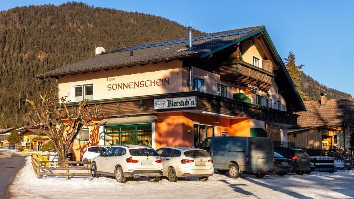 Ein gemütliches Gasthaus namens "Sonnenschein" in einer winterlichen Landschaft. Autos stehen vor dem Gebäude, umgeben von schneebedecktem Boden und Bergen. | © Michis Bierstubn