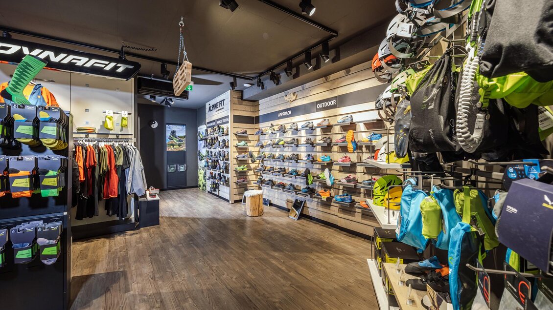 Ein gut gestalteter Sportladen mit verschiedenen Outdoor-Schuhen und -Bekleidung. Die Wände sind mit vielen Produkten ausgestellt, und der Boden ist aus Holz. | © Mountain Shop Schladming