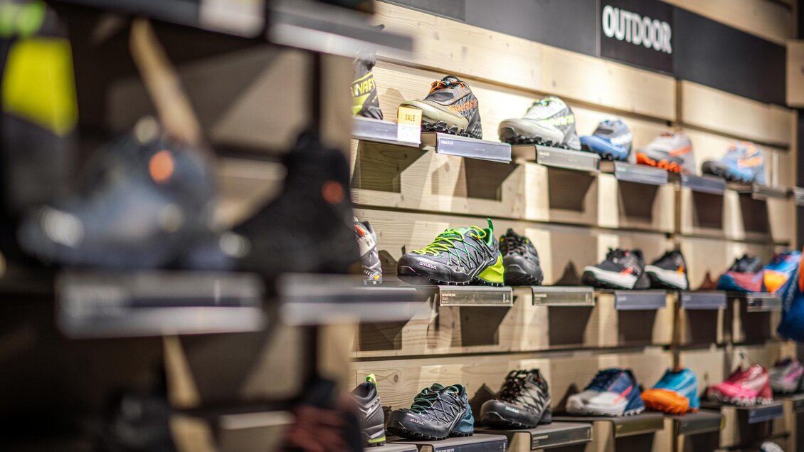 Ein Regal mit verschiedenen Outdoor-Schuhen in verschiedenen Farben und Designs. Die Schuhe sind ordentlich aufgereiht und gut sichtbar. | © Mountain Shop Schladming