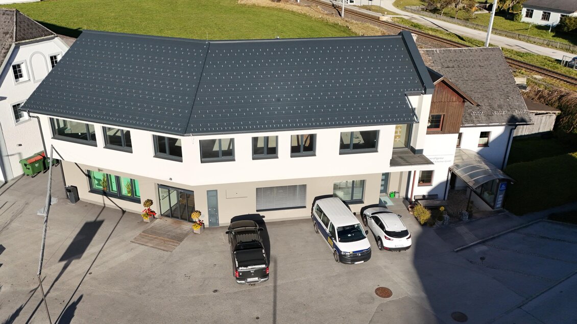 Ein modernes Gebäude mit einer dunklen Dachdeckung und großen Fenstern. Es gibt mehrere Autos vor dem Gebäude und einen grünen Rasen im Hintergrund. | © Gemeindeamt Sölk