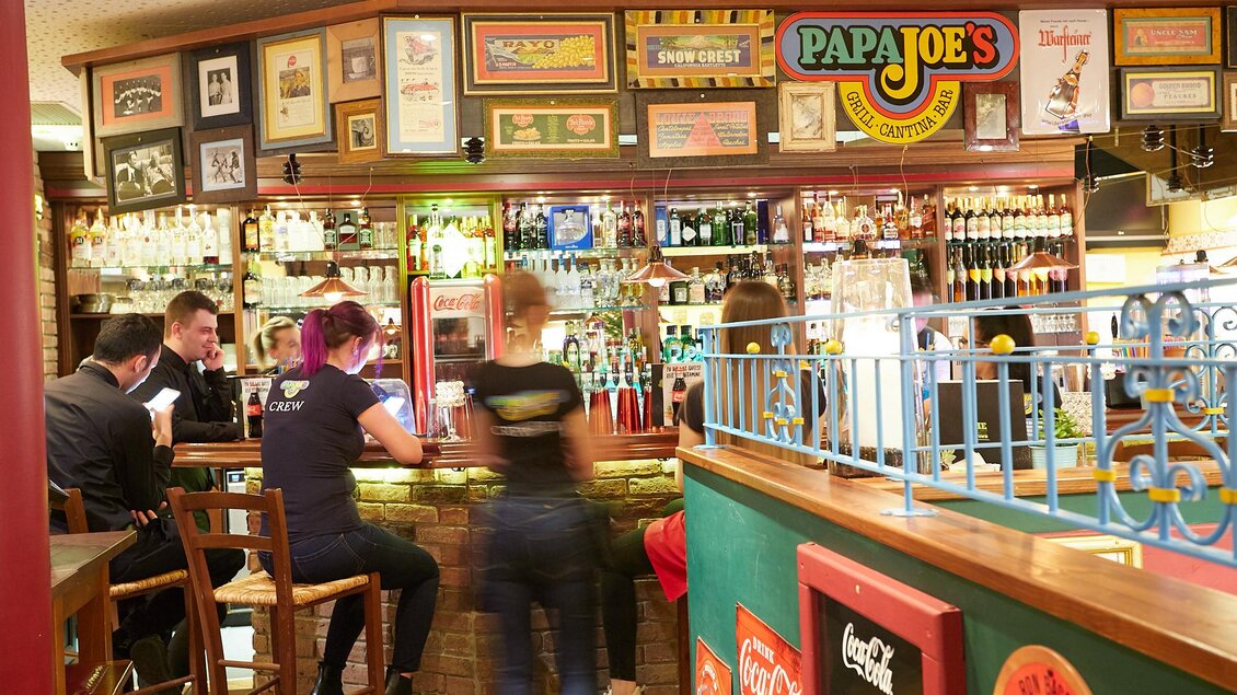 Eine gemütliche Bar mit einer gut sortierten Theke. Im Hintergrund sind viele Spirituosen und Bilder an den Wänden zu sehen. | © PhotoINstyle - Brigit Steinberger