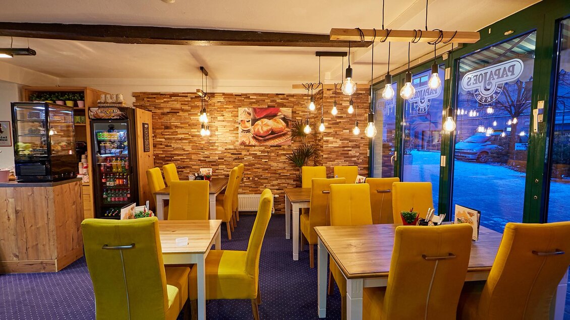 Ein gemütliches Restaurant mit gelben Stühlen und Holztischen. Große Fenster sorgen für viel Licht und eine angenehme Atmosphäre. | © PhotoINstyle - Brigit Steinberger