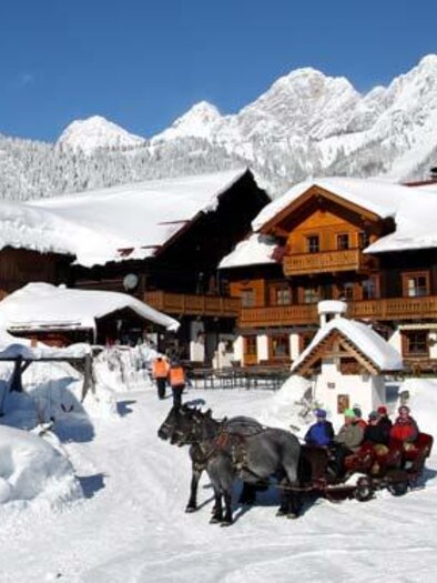 A picturesque winter landscape with a traditional wooden house and a snowy yard. Horse-drawn sleigh rides and relaxed people create a cozy atmosphere. | © Ederhof
