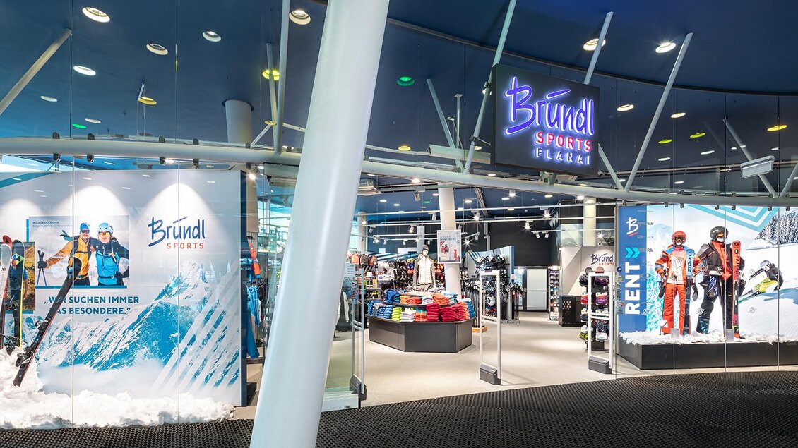 Ein moderner Sportladen mit einer großen Auswahl an Wintersportausrüstung. Die Fassade zeigt Ski und passende Bekleidung in einem einladenden Ambiente. | © Woeckinger