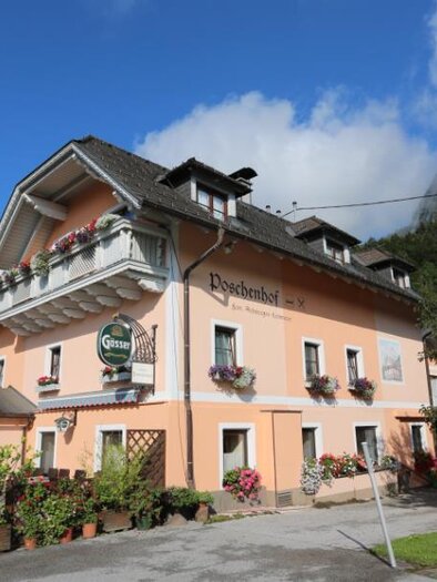 A charming orange building with balconies and flower boxes. Surrounded by green landscape and blue sky. | © Poschenhof