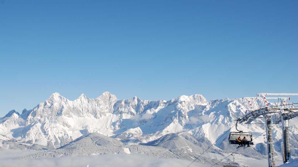 Eine schneebedeckte Berglandschaft mit strahlend blauem Himmel. Im Vordergrund ist ein Skilift zu sehen. | © Reiteralm Bergbahnen